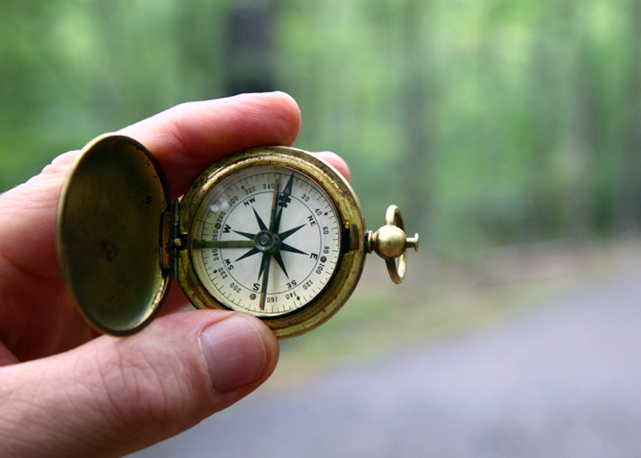 Hand holding a compass on trail